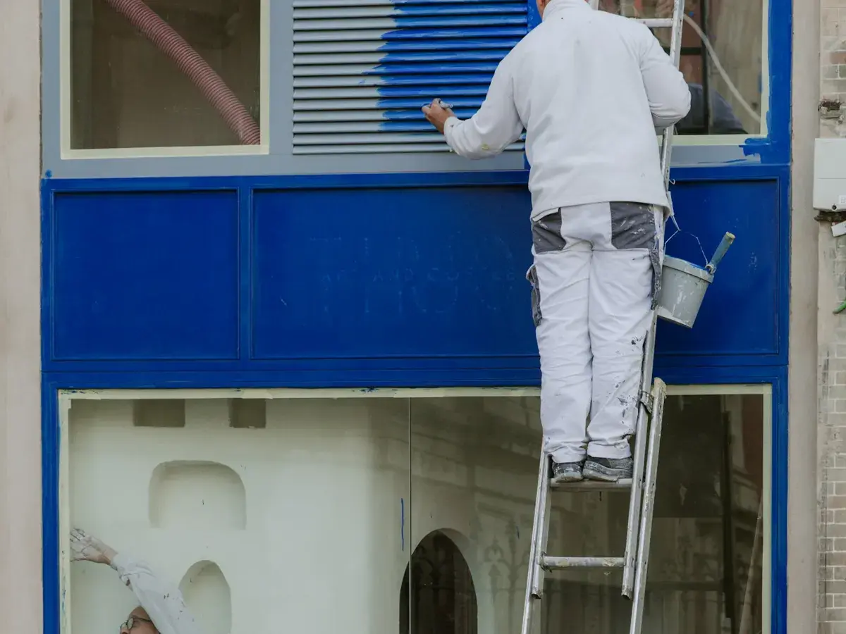 Maler streicht ein Fenster und Fensterrahmen von der Leiter aus
