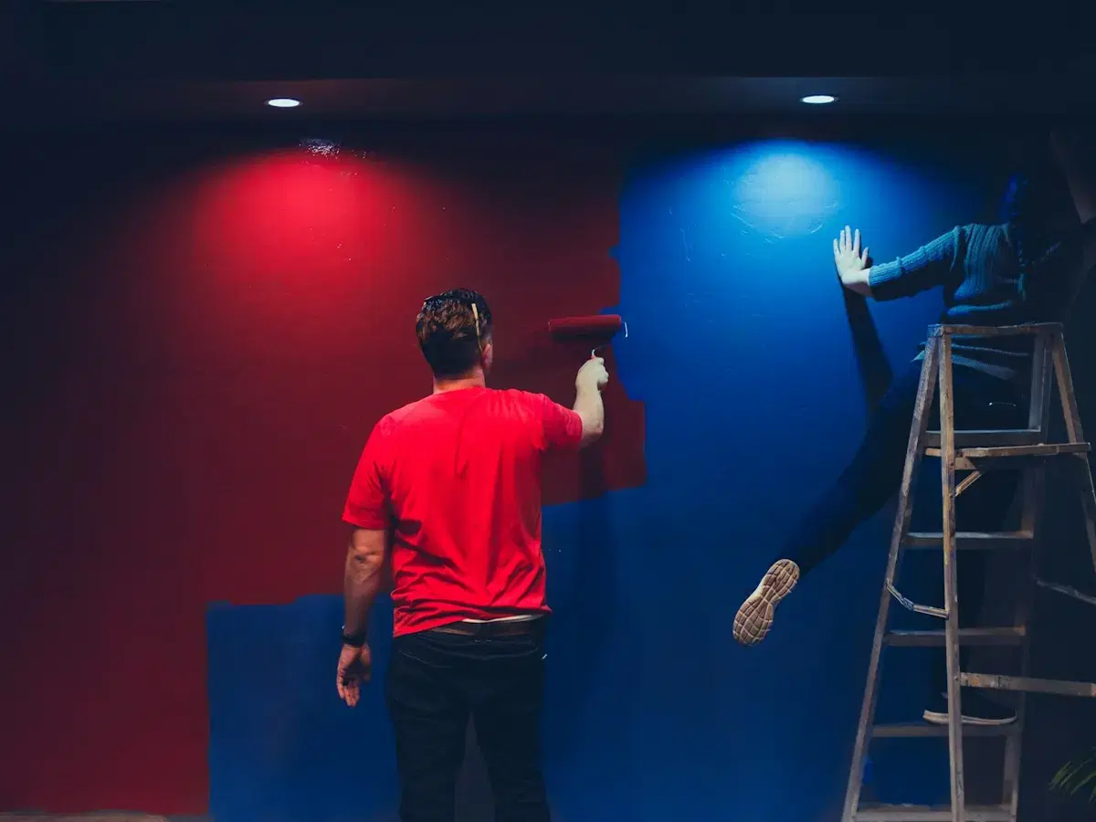 Maler gestaltet eine Wand in kräftigem Rot und Blau